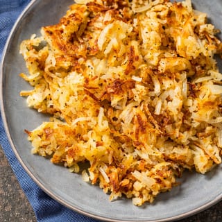 Golden shredded potatoes, pan-fried to a crisp texture, served with a side of ketchup.