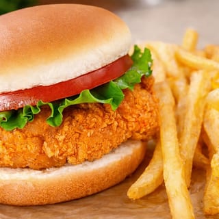 Fried chicken breast sandwich. Served with lettuce, tomatoes, pickles, onions and fries.