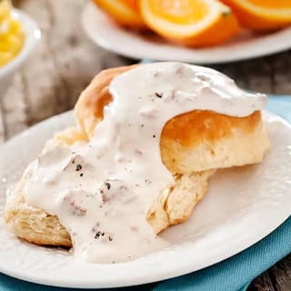 A hearty bowl featuring a flaky biscuit topped with rich, creamy chicken gravy.