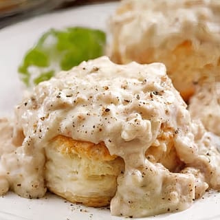 A flaky biscuit smothered in creamy sausage gravy, seasoned with black pepper.