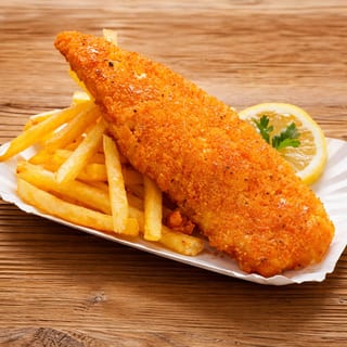 Crispy breaded basa fillet served with a side of golden fries and a lemon wedge.