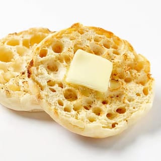 Two toasted English muffin slices topped with a pat of butter.