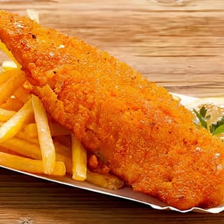 Crispy breaded basa fillet served with a side of golden fries and a lemon wedge.
