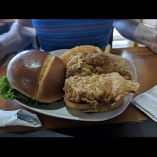 Pork chop sandwich. Served with lettuce, tomatoes, pickles, onions and fries.