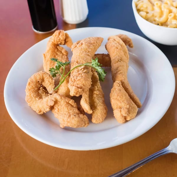Golden-brown fried fish and shrimp on a white plate with a side of macaroni and cheese.