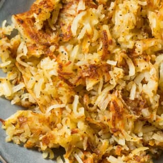 Golden shredded potatoes, pan-fried to a crisp texture, served with a side of ketchup.