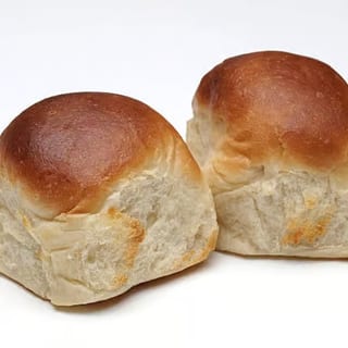 Two golden-brown dinner rolls with a soft and fluffy interior.